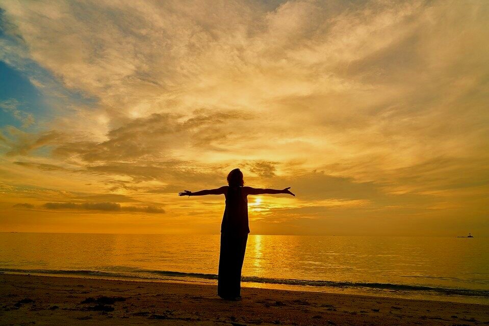 Woman at sunset with open arms